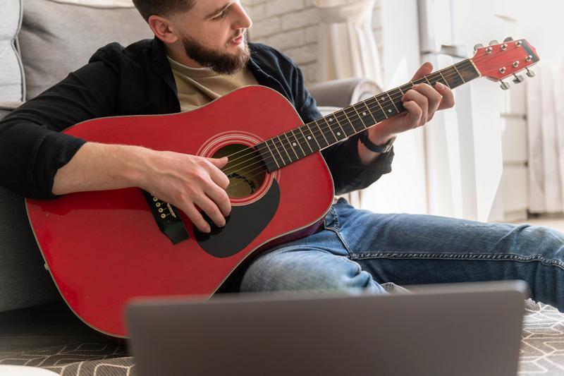 close-up-man-playing-guitar-floor